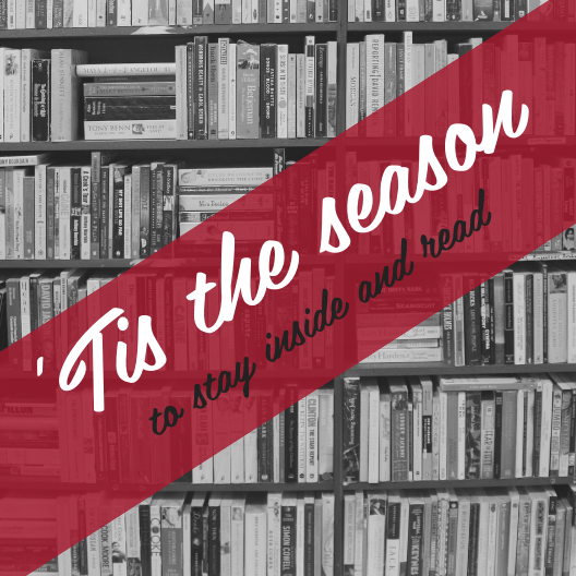 5" x 5" laminated card. Shelves of books in black and white in the background. "'Tis the season" in large script white font with "to stay inside and read" in black smaller script font, both against a red banner diagonally from the bottom left to top right corners.