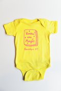 Yellow onesie with "Books Are Magic" in script font design against a book cover.