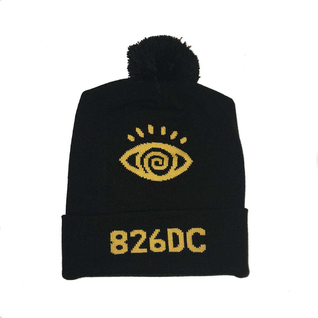 Black ski hat made of cotton blend. Features eye illustration at the top with "826DC" at the brim; both in gold.