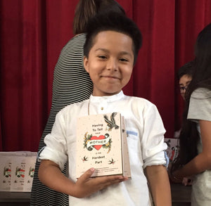 Young Latino boy holds a copy of the book to his chest on his right.