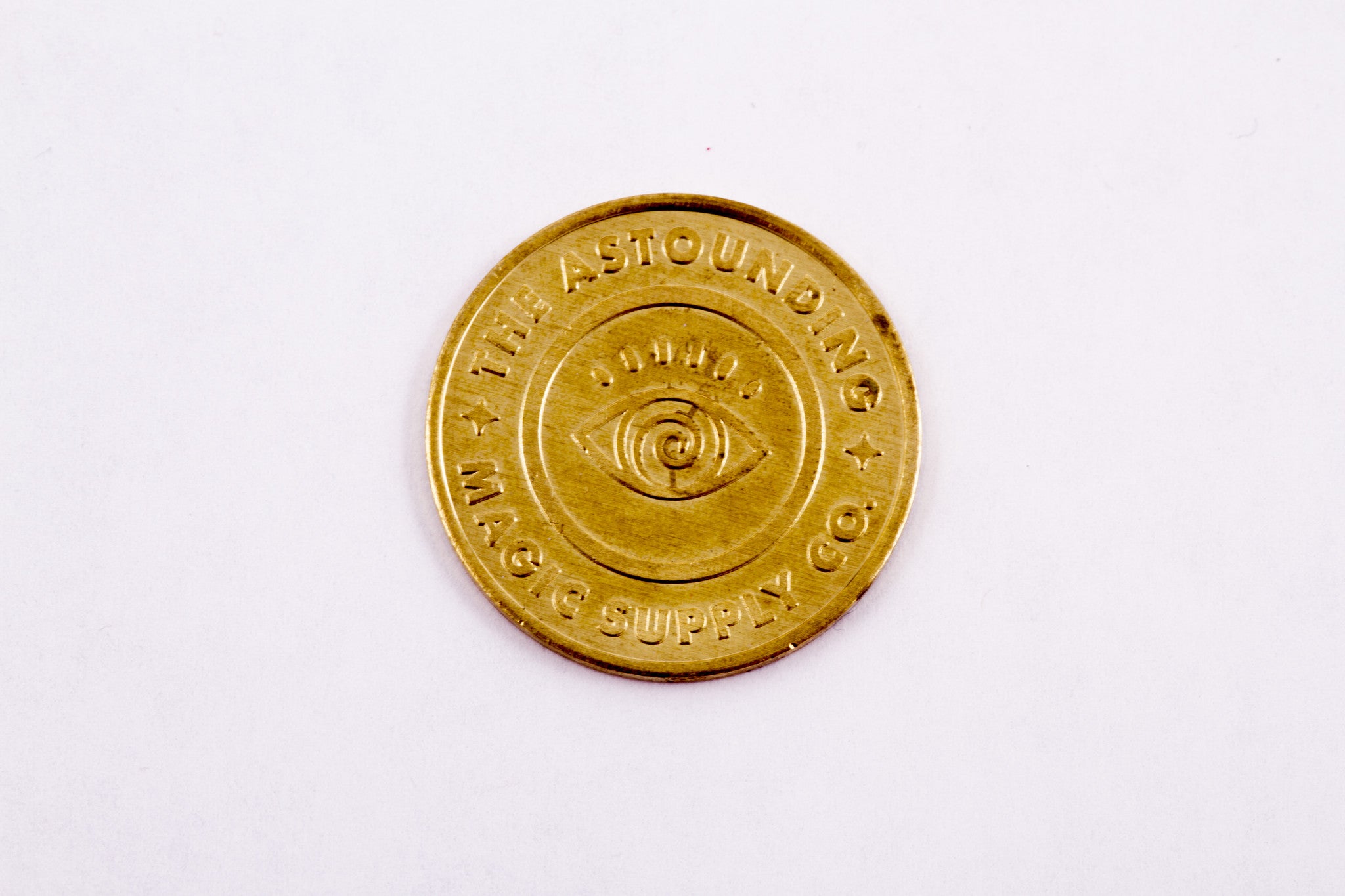 Quarter-sized gold coin. Eye on one side. Cross wands on the other side. Tivoli's logo on both sides.